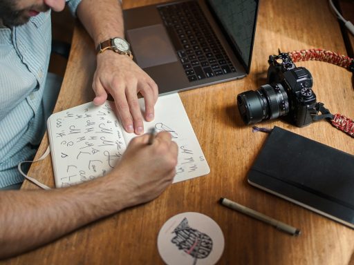 man writing on paper in front of DSLR