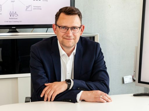 Man in suit and glasses sits at table