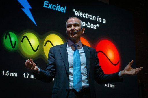 Man in suit presents science concept with colorful graphics.