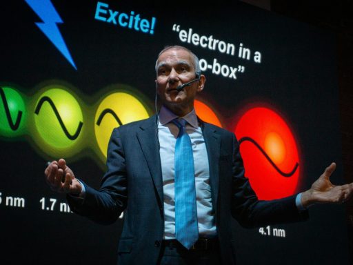 Man in suit presents science concept with colorful graphics.