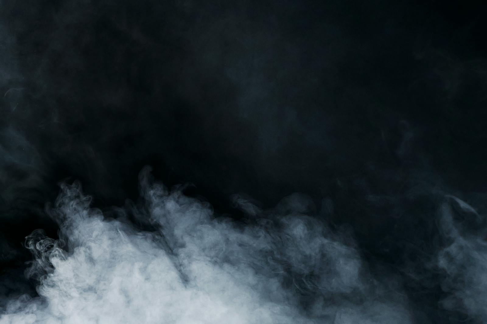 Ethereal white smoke on a black background creates a sense of mystery and depth.
