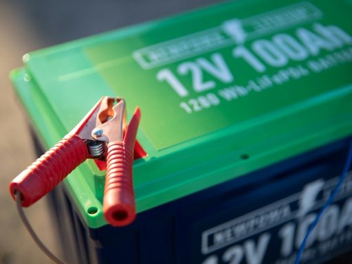 a red and green battery with a pair of pliers attached to it