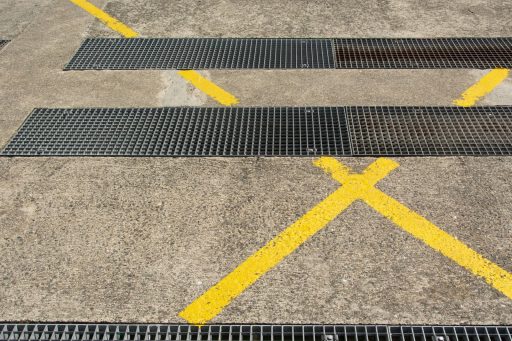 Detailed view of urban asphalt with metal grilles and yellow markings.