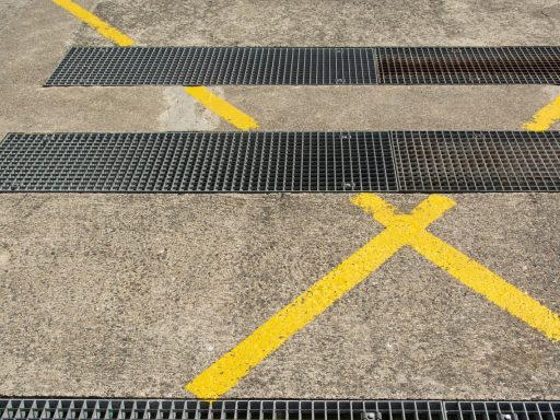 Detailed view of urban asphalt with metal grilles and yellow markings.