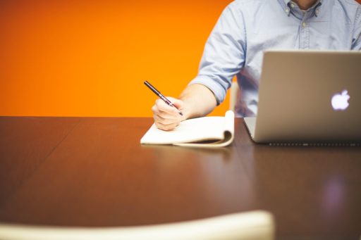 Ondernemer die zijn missie en visie opschrijft in een notitieboek aan een bureau