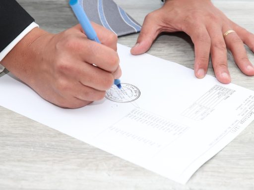 Ondernemer ondertekent papieren bij een bedrijfsoverdracht aan een vergadertafel
