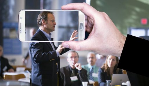 Een man spreekt zelfverzekerd voor een publiek op een zakelijk podium